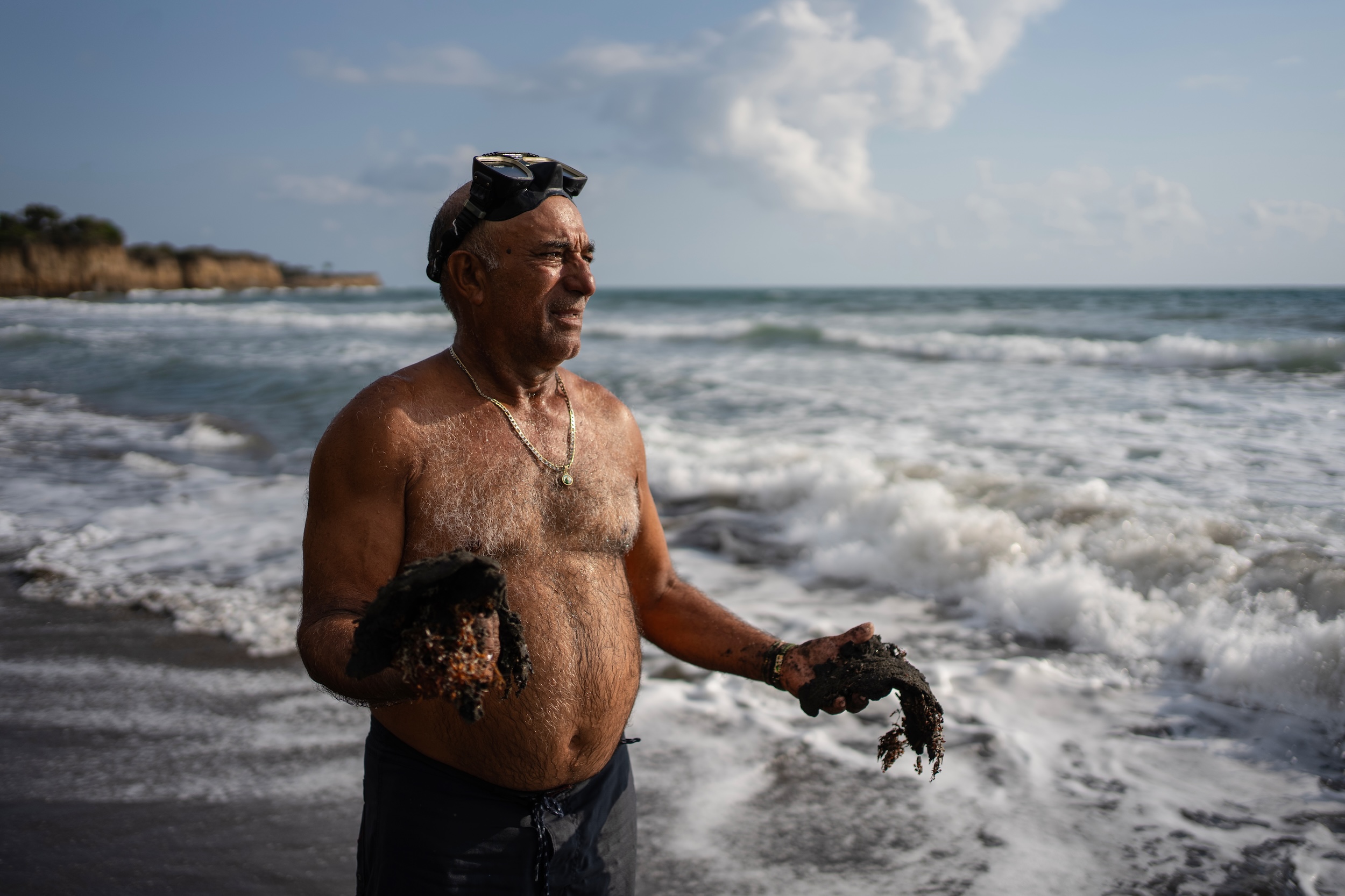 El pescador Leopoldo Salgado sostiene grumos de residuos de petróleo recogidos en la costa días después de un derrame de petróleo en el Golfo de México